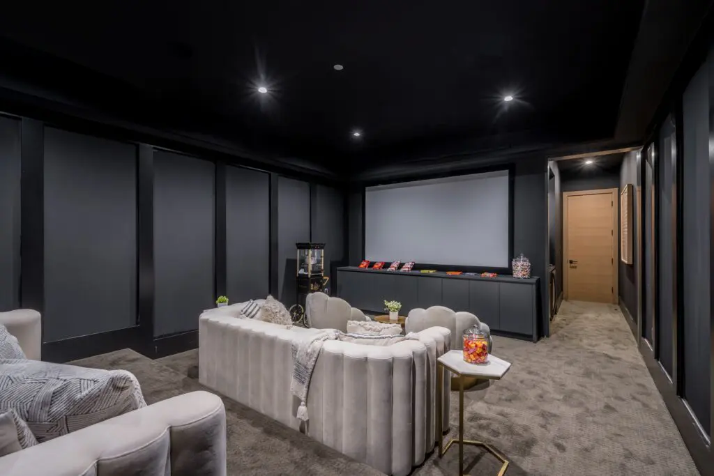 Modern home theater room with plush curved seating and a large projection screen.